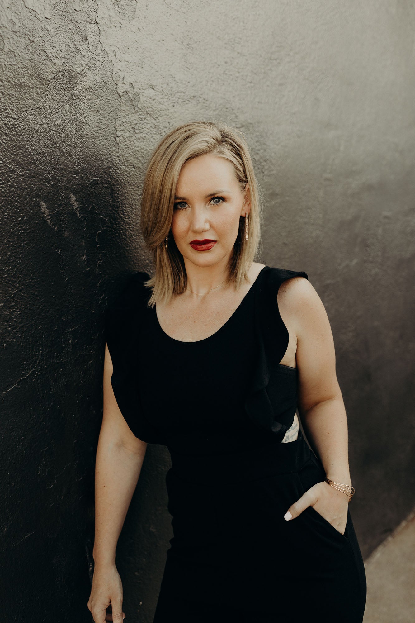 Portrait of Shaylee against a black and grey concrete wall.