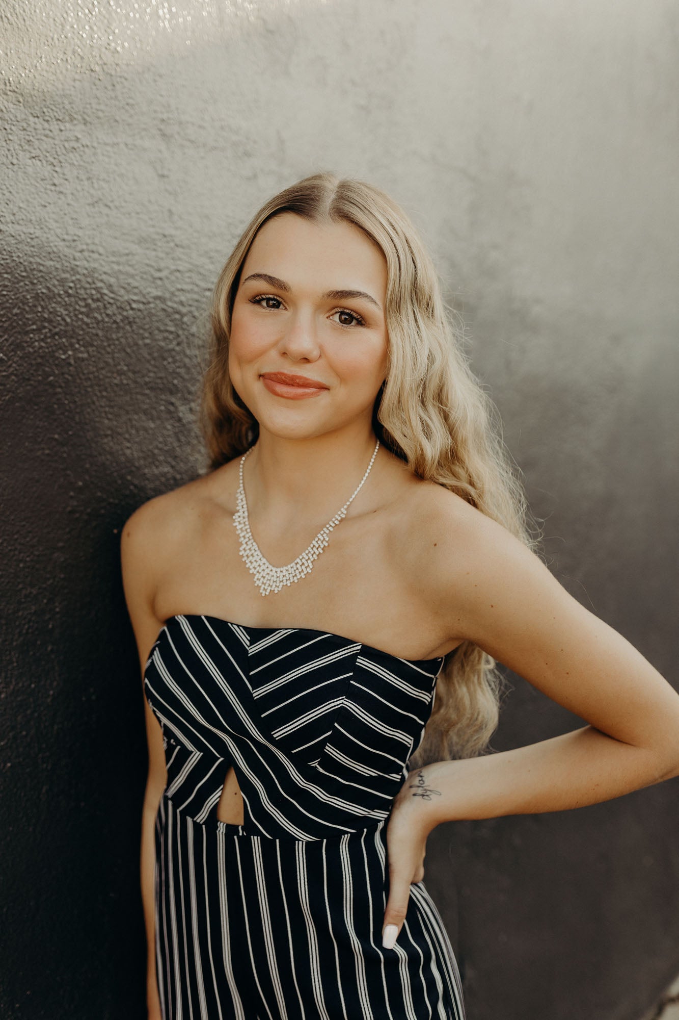 Portrait of Hadlee against a black and grey concrete wall.