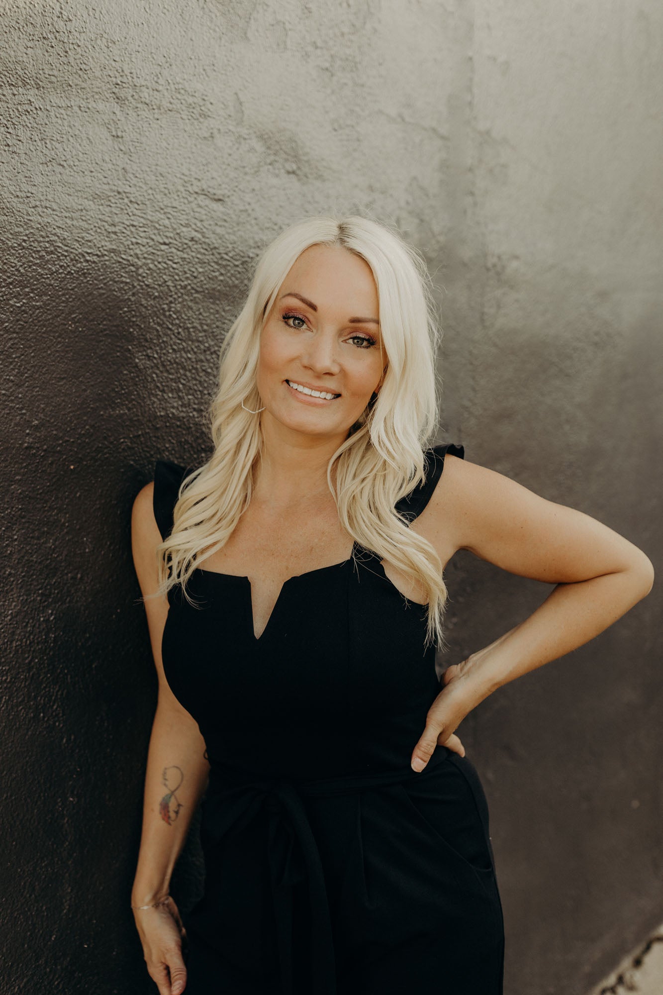 Portrait of Rebekah against a black and grey concrete wall.